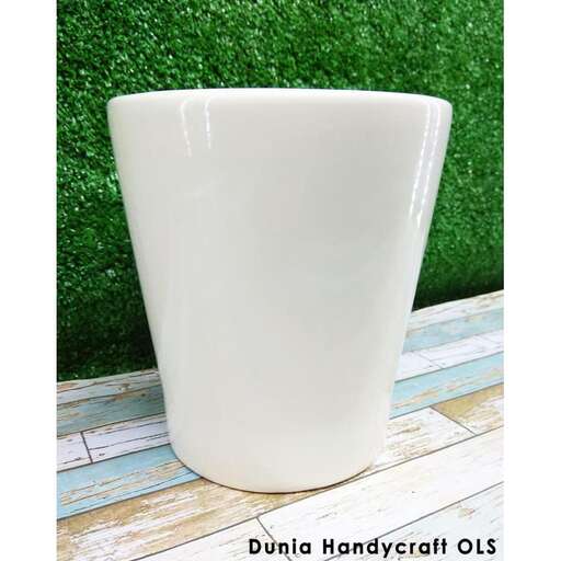 a white vase sitting on top of a wooden table.