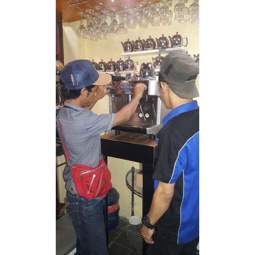 two men are standing in a room with a coffee machine.