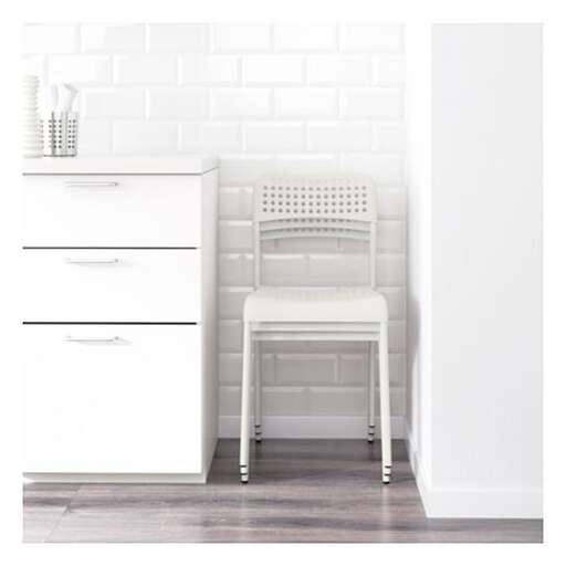 a white chair sitting in a kitchen next to a white wall.