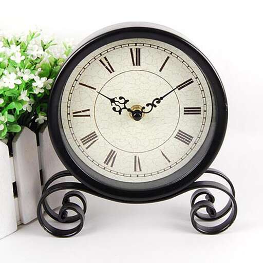 a clock and a flower stand on a table.