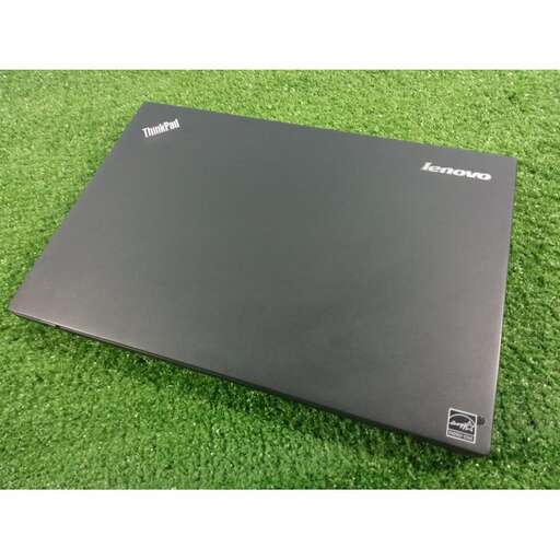 a laptop sitting on top of a lush green field.