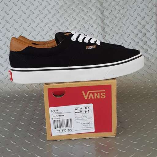 a pair of black vans with white soles on a metal surface.