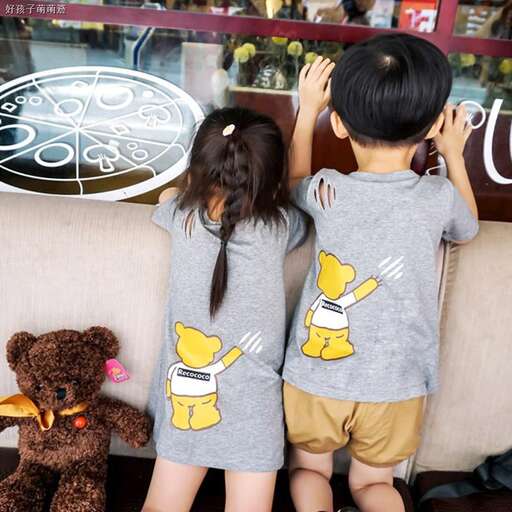 two children are standing on a couch and looking at a sign.