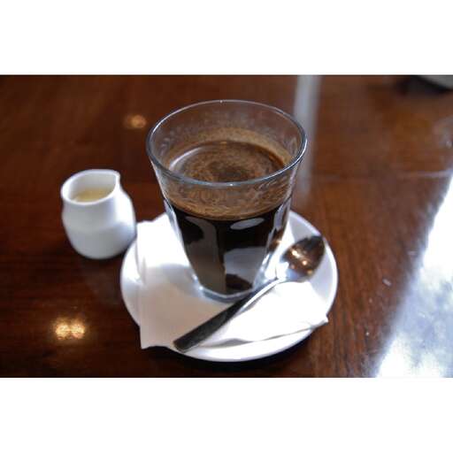 a cup of coffee on a plate with a spoon.