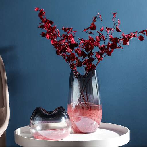 a vase with red flowers in it on a white table.
