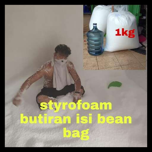 a small doll sitting on a blanket next to a bag of water.