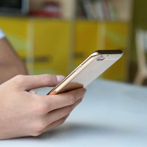 a person holding a smart phone in their hands.