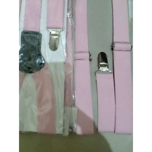 a pair of pink and white baby clothes hanging from a hook.