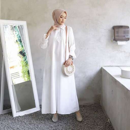 a woman in a white dress standing in front of a mirror.