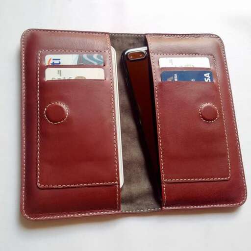 a red leather wallet with a brown leather cover and a brown leather strap.