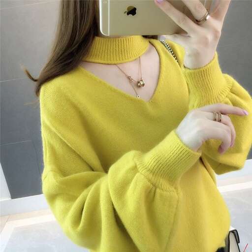 a woman in a yellow sweater holding a cell phone.