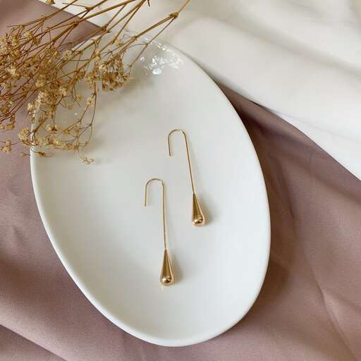 two gold hooks on a plate with a flower on it.