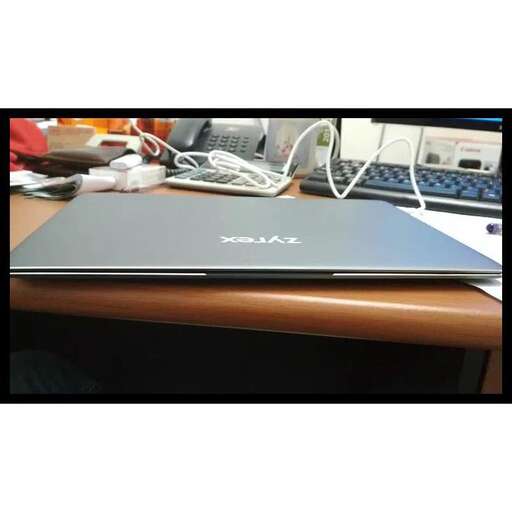 a laptop sitting on a desk with a mouse and wires.