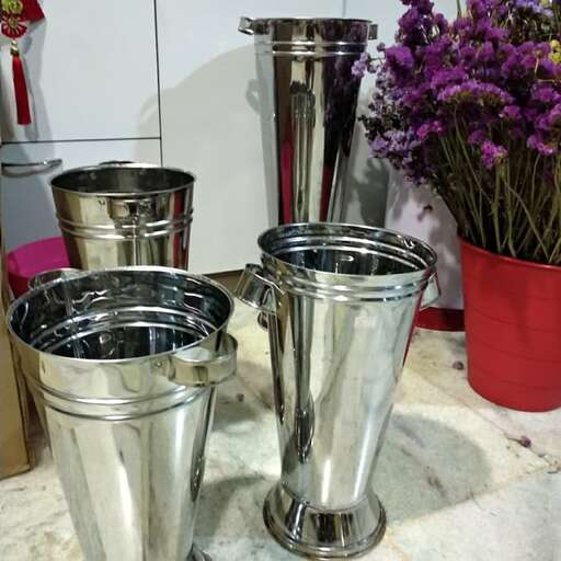 a table topped with silver metal containers and flowers.