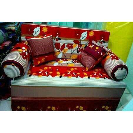 a red and white couch with pillows and pillows.