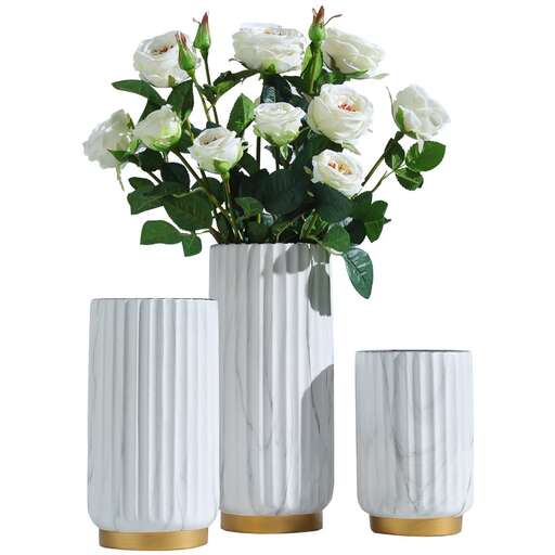 a white and gold vase with a white flower in it.