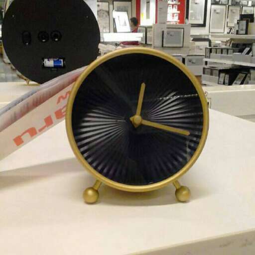 a clock that is on a table with a person standing next to it.