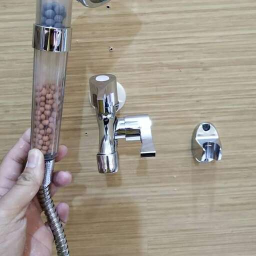 a person holding a faucet over a wooden surface.