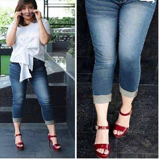 a woman in jeans and a white shirt talking on a cell phone.