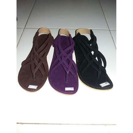 a pair of brown sandals sitting on a white tile floor.