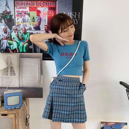 a girl in a skirt and a blue shirt is posing for a picture.