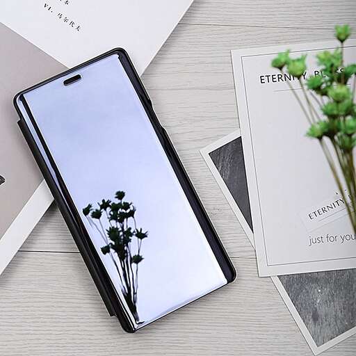 a smart phone is sitting on a table with a plant in it.