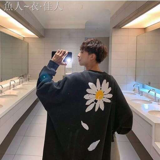 a man in a black jacket is taking a picture of a flower on his shirt.