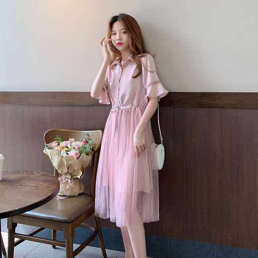 a woman in a dress standing in front of a table.