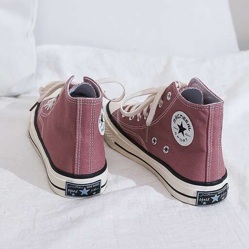 a pair of purple and white sneakers on a bed.