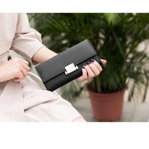 a woman holding a black purse in her lap.