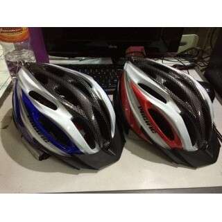 two helmets are sitting on a desk next to a computer.