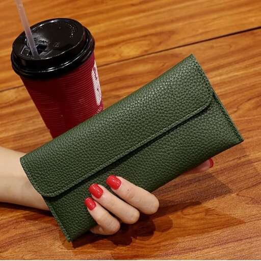 a woman's hand holding a wallet with a drink in it.