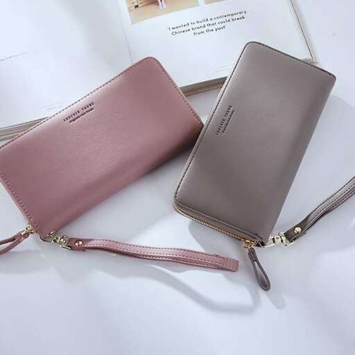 a pink leather wallet sitting on top of a white surface.