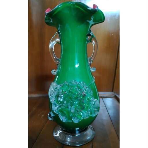 a green vase with a glass piece on it.