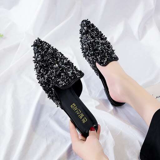 a woman is holding a pair of black shoes.