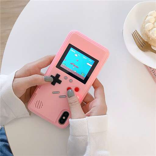a person holding a pink cell phone on a table.