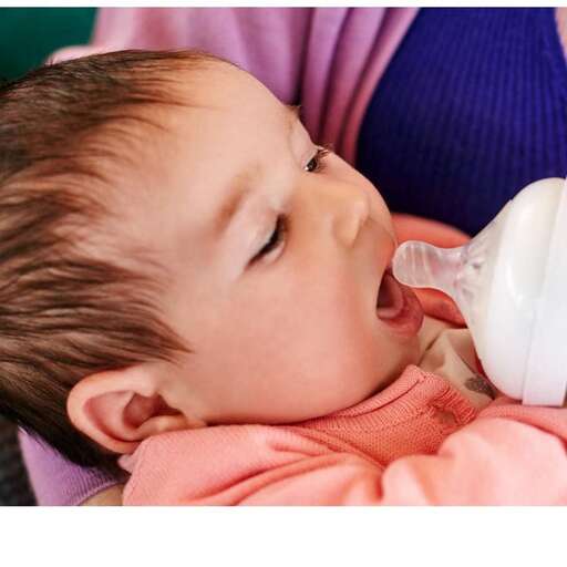 a baby drinking from a bottle while sitting on a couch.