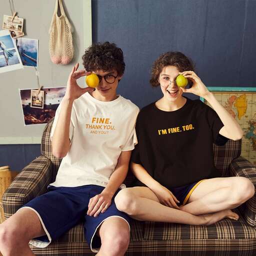 two people sitting on a couch drinking from a glass.