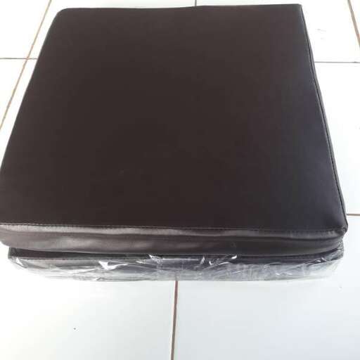 a black suitcase on a tile floor with a plastic cover.