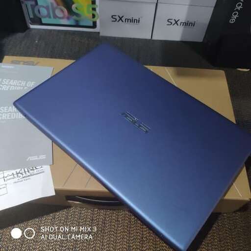 a blue laptop computer sitting on top of a brown carpet.