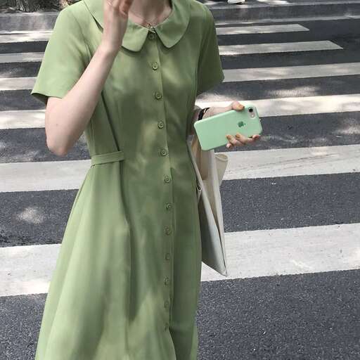 a woman in a green dress talking on a cell phone.
