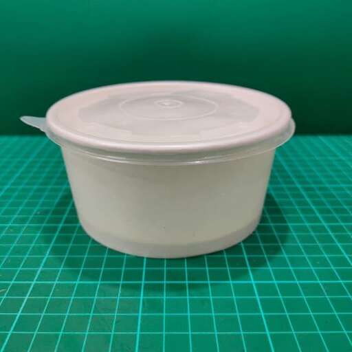 a plastic container with a lid on a green surface.