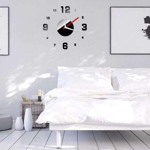 a white bed with a clock on the wall above it.