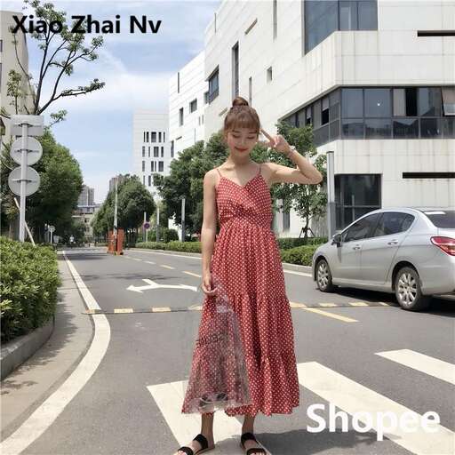 a woman in a red dress and sandals walking down a street.