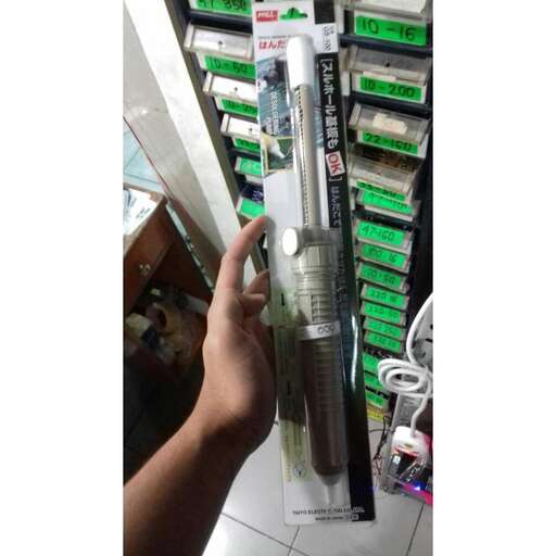 a hand holding a tube of batteries in a shelf.