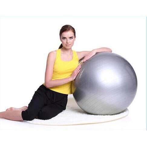 a woman sitting on a mat with a large ball.