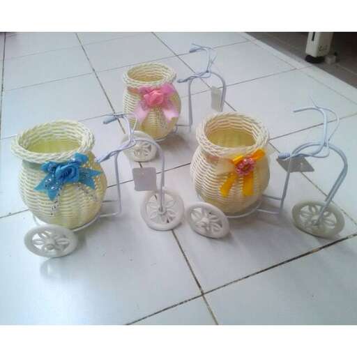 three jars with flowers on them on a tiled floor.