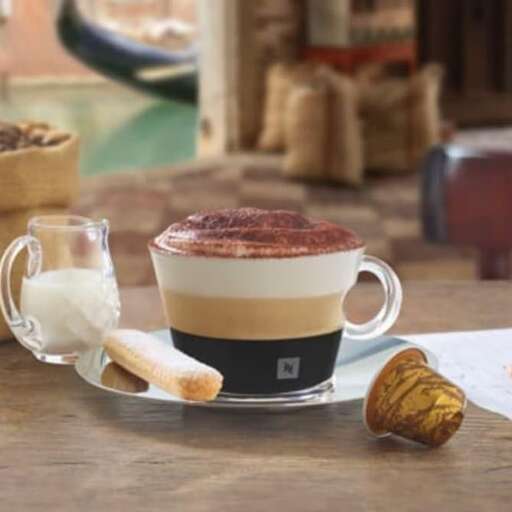 a cup of coffee sitting on a table next to a plate of bread.