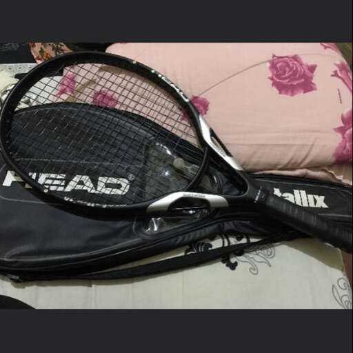 a tennis racket is laying on a bed.