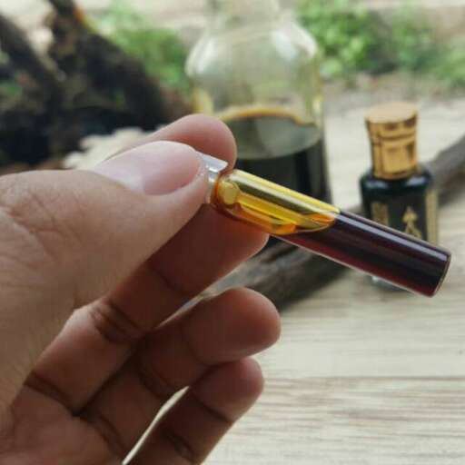 a hand holding a bottle with a cork in it.